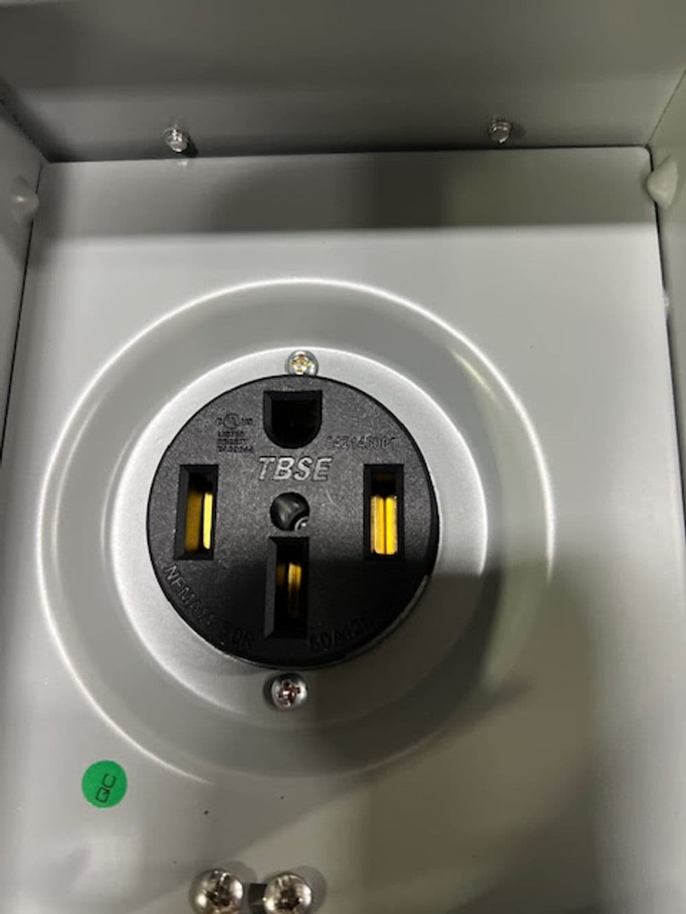 NEMA 14-50R electrical outlet with three vertical slots and green indicator in metal box.
