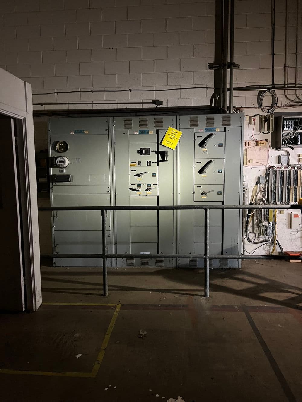 Electrical panel in dimly lit industrial space, marked with caution sign.