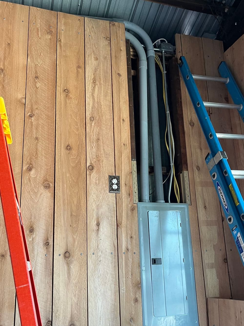 Interior construction scene showing wooden walls, electrical panel, and ladders for access.