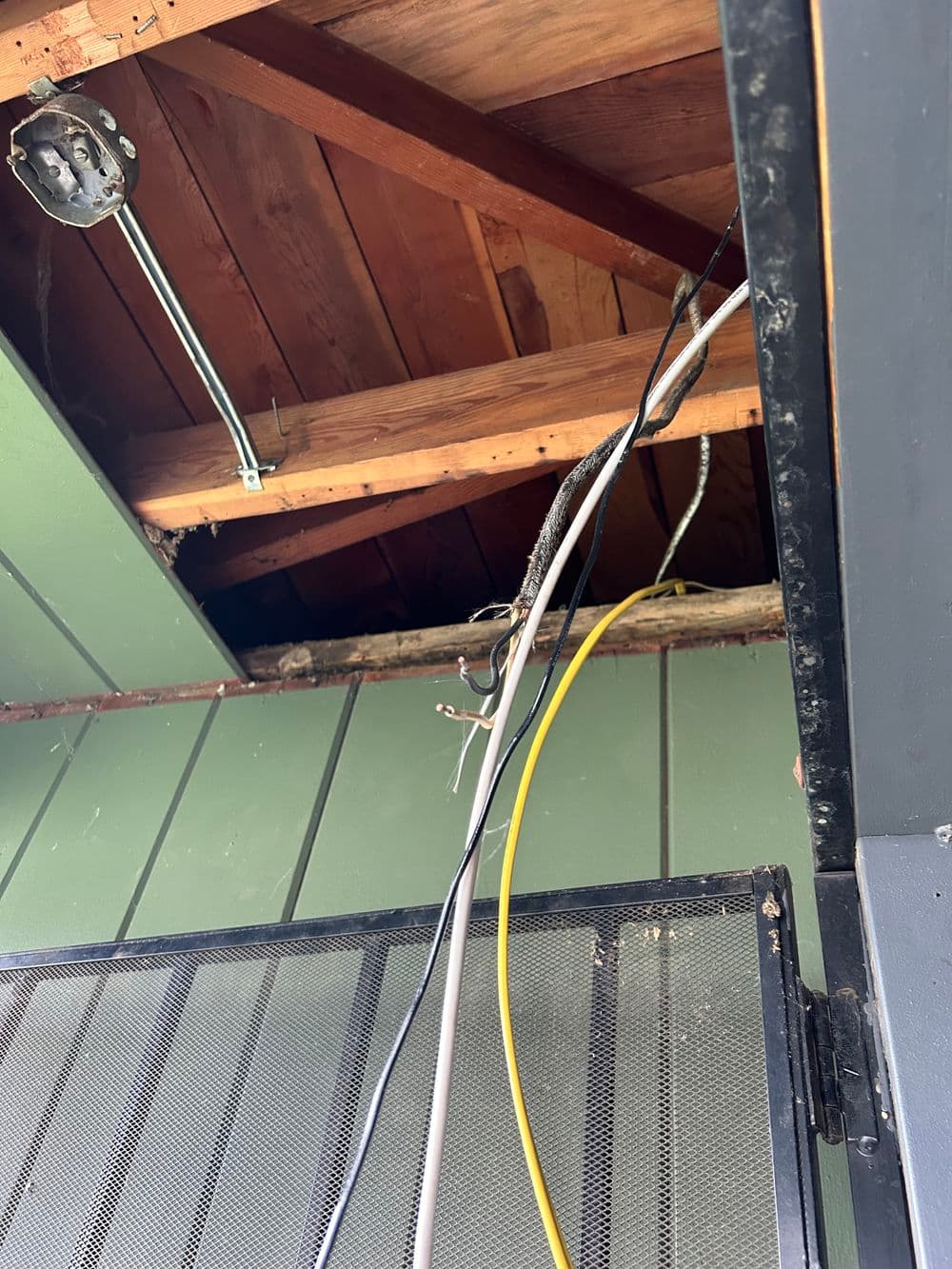Exposed wires and wooden beams in ceiling area, showing electrical installation work needed.