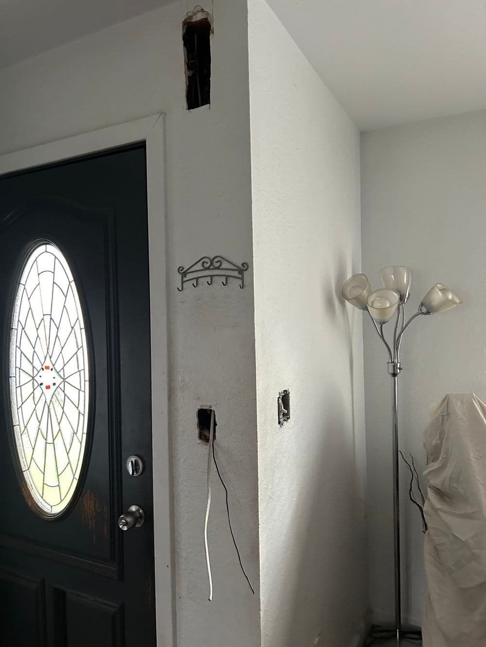 Entryway featuring a decorative door, a wall lamp, and exposed electrical outlets.