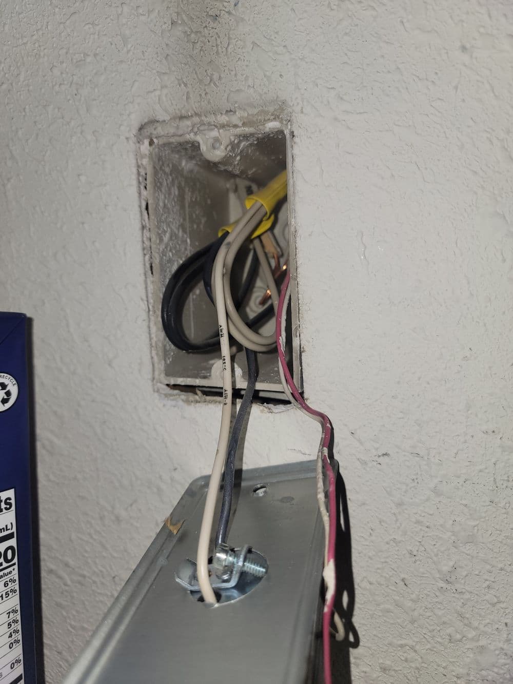 Electrical wiring inside a wall cavity with exposed connections and junction box.