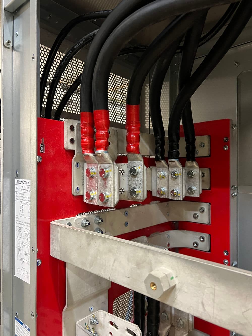 Electrical connections in a red panel with multiple high-voltage cables and connectors.