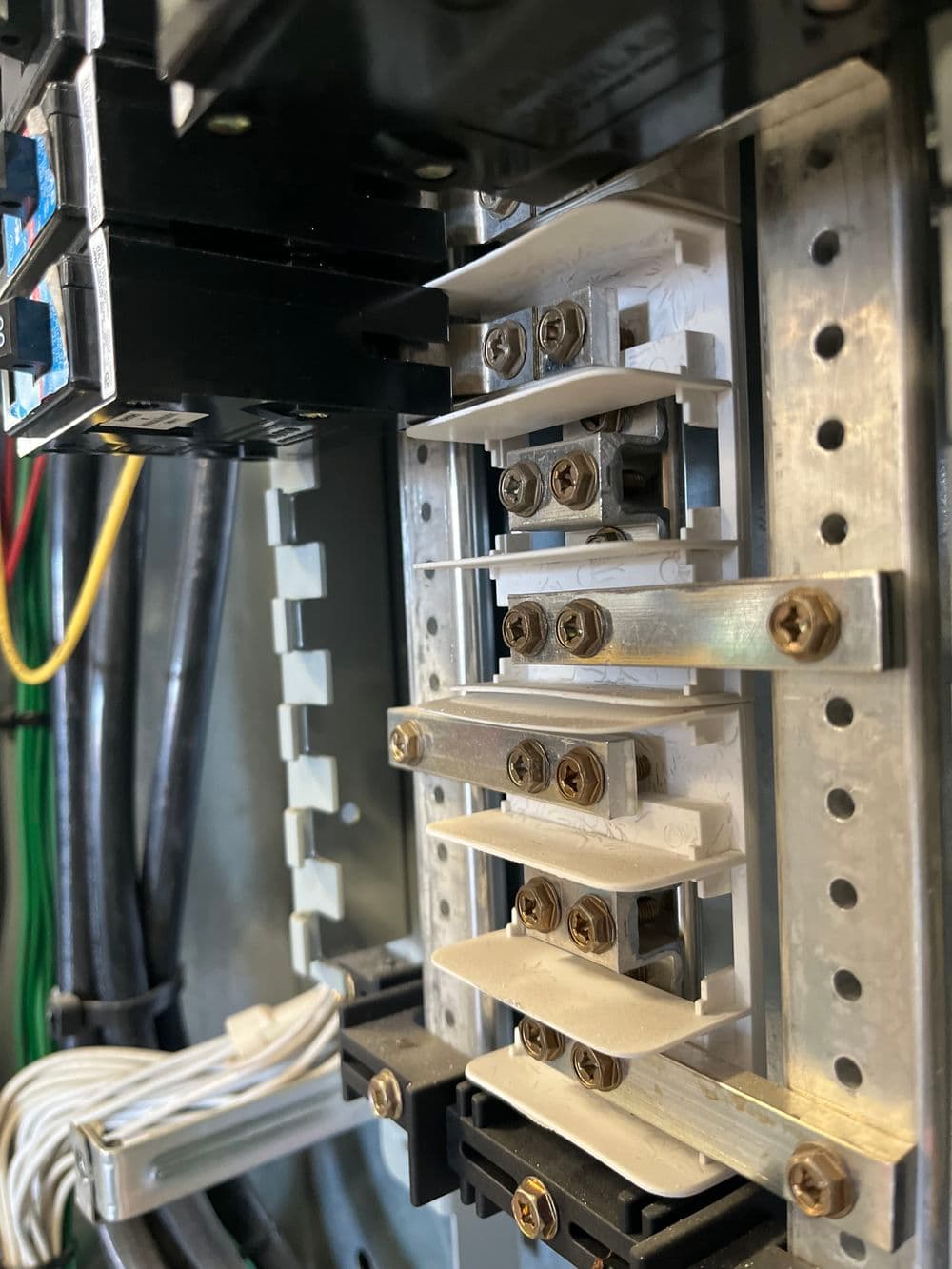 Electrical panel with circuit breakers and bus bars for power distribution.